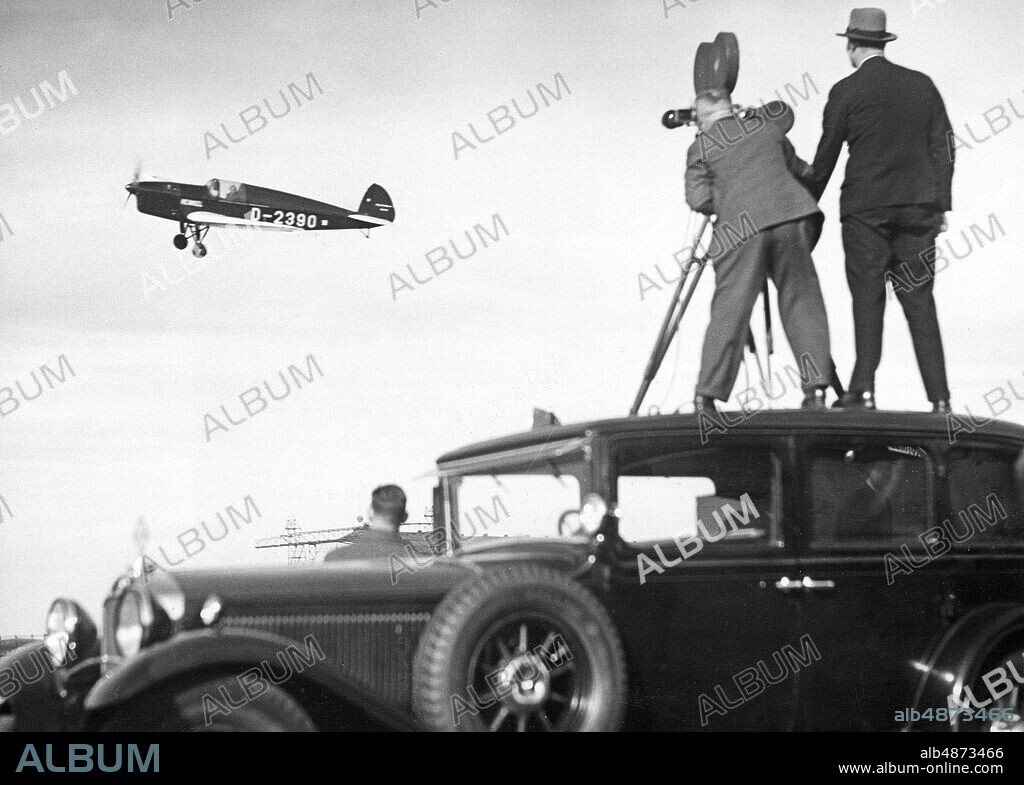 GERMANY BERLIN 1930s. Original text ... ELLI BEINHORN AGAIN ON WORLD FLIGHT. The outstanding German pilot Elli Beinhorn, who had just received the Hindenburg trophy from the Reich President for her great flying achievements in 1932, has started a new world flight, which should be a commercial flight for Germany and its national awakening. The pilot completed the first stage of the flight from Berlin to Constantinople in 10 3/4 hours without a stopover, thus completing a new record performance with her Heinkel sports aircraft, which owns an 80 PS Hirth engine. The aviator undertakes her air travel on behalf of the Berlin local advertiser. U.B.z. the take - off of the aviator, filmed by Ufa operators (in the foreground). Photo: Scherls Bilderdienst / AB Text & Bilder / SVT / code: 5600 BAE201 b / w copy E Beinhorn, 1907-2007, German female aviation pioneer. Long-haul flights Journal film Photographers persons: ELLY BEINHORN * sites: BERLIN; GERMANY PhotoDate: 193? - ?? - ??.