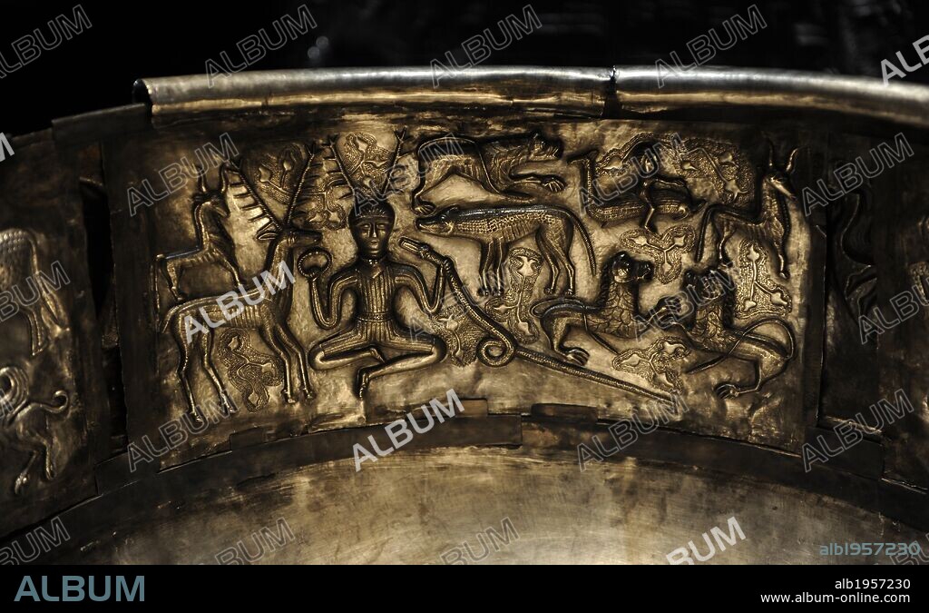 The Gundestrup cauldron. Decorated silver vessel, thought to date between 200 BC and 300 AD, placing it within the late La Te_ne period or early Roman Iron Age. Gundestrup in the Aars parish of Himmerland, Denmark.  Horned male figure seated in a central position. He holds a torc in his right hand and the ram-horned serpent in his left. Attended by a stag on his right and a boar on his left. Is generally identified as the god Cernunnos.  National Museum of Denmark.