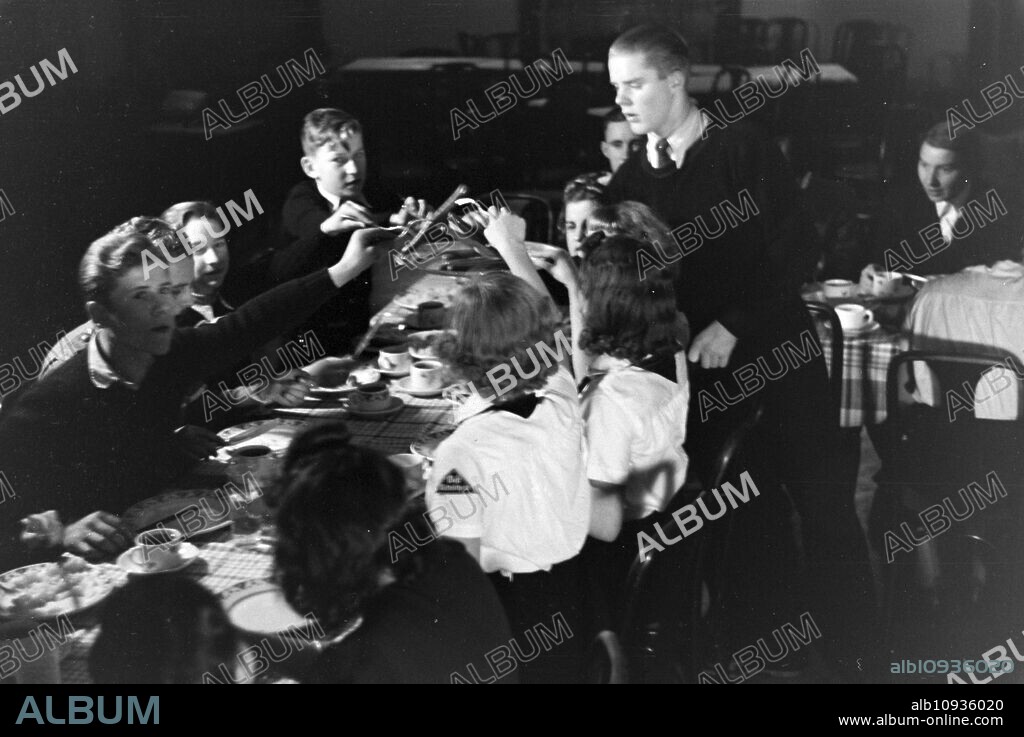 A figureskating group of the Hitler Youth wearing uniforms of the HJ and BDM during dinner after a training, Germany 1930s.
