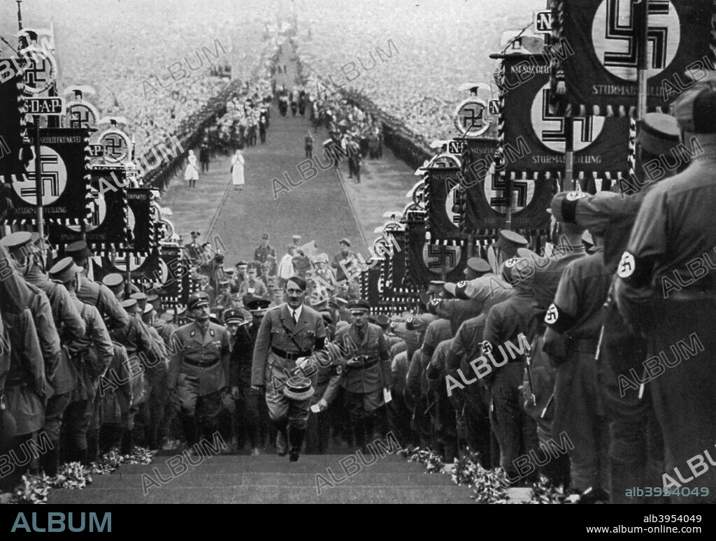 Adolf Hitler at the Bückeberg Harvest Festival, Germany, 1 October 1934. Hitler (1889-1945) climbing steps between ranks of Nazis holding swastika banners. Huge crowds can be seen in the background. The Nazis staged a Reich harvest festival at the Bückeberg annually from 1933 until 1937. A print from Adolf Hitler. Bilder aus dem Leben des Führers, Hamburg: Cigaretten/Bilderdienst Hamburg/Bahrenfeld, 1936.