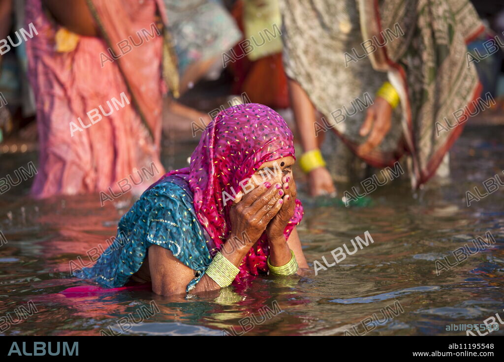 Indian Hindu pilgrim woman bathing in The Ganges River at Dashashwamedh Ghat in Holy City of Varanasi, Benares, India.
