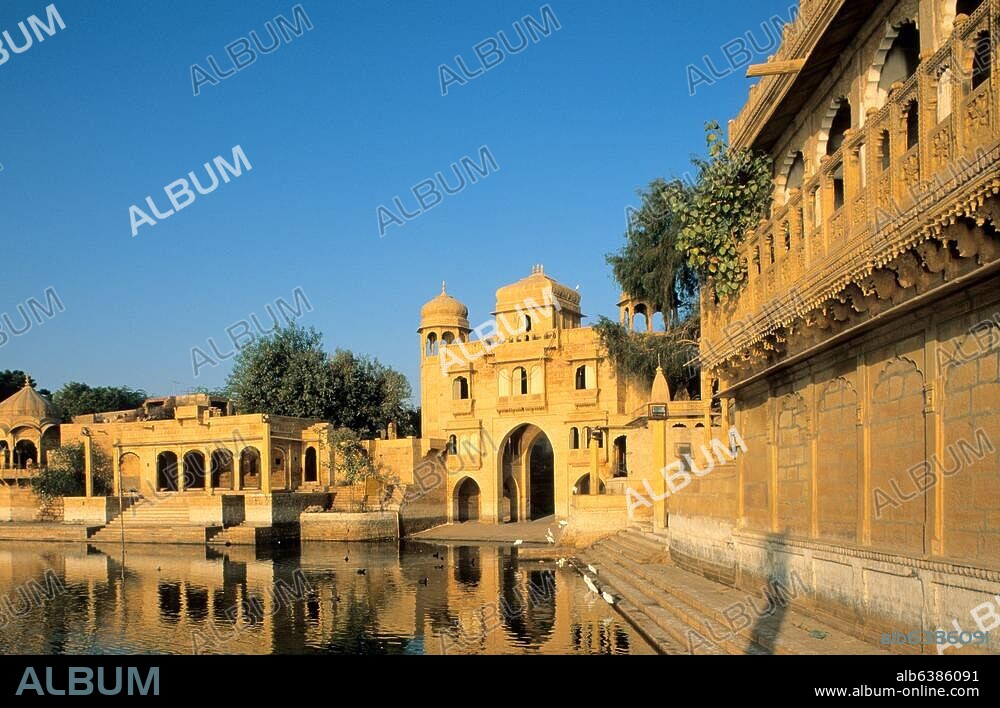 Jaisalmer (Rajasthan, Indien), Gadi Sagar (künstlicher See, Wasserreservoir, angelegt 1367 von Rawal Gadsi Singh).-Teilansicht mit Tor Tilonki-Pol, Tempeln und Pavillons am Ufer.-Foto, undat.