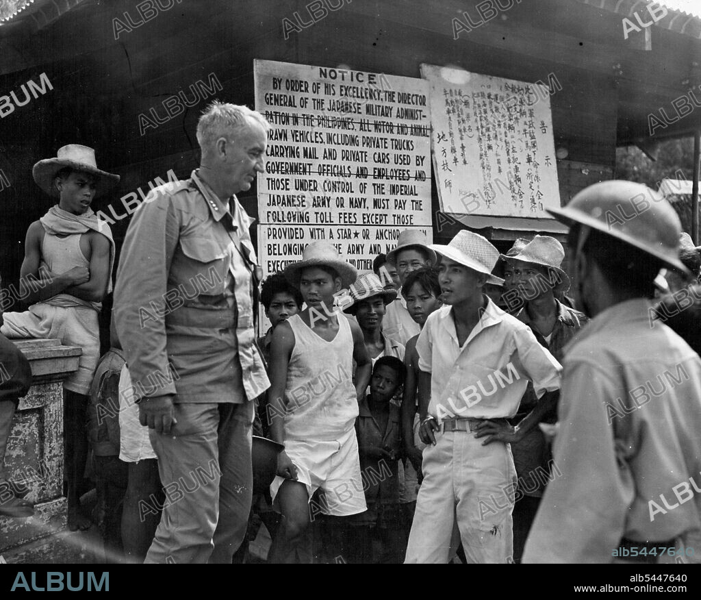 Buna Veteran in Philippines - Lt.-Gen. Robert Eichelberger, commander of the U.S. 8th Array, speaks to Filipinos congregated near the Zapote River bridge, about ten miles from Manila. Behind him is a toll fee notice posted by the Jap army Eichelberger was in command of the U.S. I Corps during the Buna campaign, the engagement stick which stopped the Jap drive toward Australia. March 12, 1945. (Photo by USA Signal Corps).