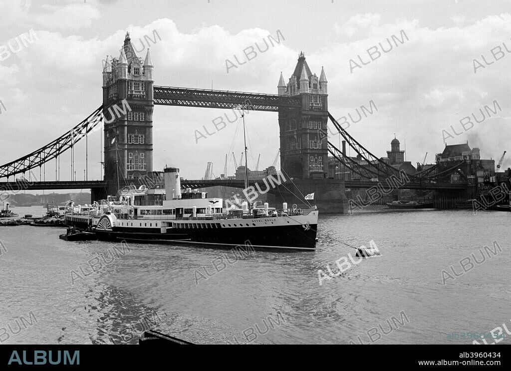 The 'Royal Eagle' paddle steamer with Tower Bridge in the background, London, c1945-c1965. The 'Royal Eagle' lies at anchor, with the famous London landmark Tower Bridge behind, designed by Horace Jones. The bridge has a movable central section which opens to allow tall ships through. The 'Royal Eagle' was one of many ships requisitioned by the Royal Navy during World War II, when it was used as an accommodation ship.