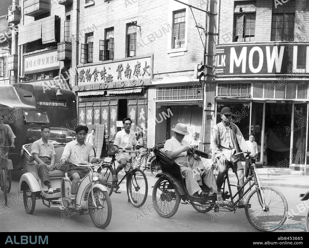 Orig. bildtext... HORSEPOWER SUPPLANTS MANPOWER ON RICKSHAW Shanghai, China. The picturesque rickshaw, hauled by a steel-muscked coolie, is on the way out in China with the appearance of the rikmobile, shown in action here on Shanghai streets. The successor to the rickshaw is a dight motorbike hooked up to a light passenger carrier. Maximum speed is 25 miles an hour and fuel consumption is 75 miles per gallon. Sixty thousand of the gadgets are now in production at the Leuton factory in Shanghai. All parts are manufactured on the spot. Orig. bildtext... KINAS RICKSHAWS HAR FÅTT EN MOTORISERAD EFTERFÖLJARE, RIKMOBILEN, SOM HÄR SES PÅ EN GATA I SHANGHAI. sites: KINA ;SHANGHAI.