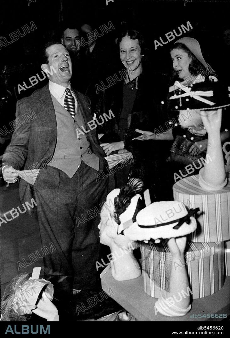 Ted Ray Backs  a Loser in a "Double" Event Shopping with Two Wives -- Pity the man who, like poor Ted Ray, radio comedian, who has two wives - one at home and one on the radio. Kitty Bluett (right). Ted's radio wife in "Ray's a laugh" is such good friends with his real wife Sybil that they insist on taking Ted out shopping together. But it is not so lovely for Ted, When you consider the havoc one wife can wreak in a man's pocket-book, just think what two can do. Picture in a London store. April 9, 1951.