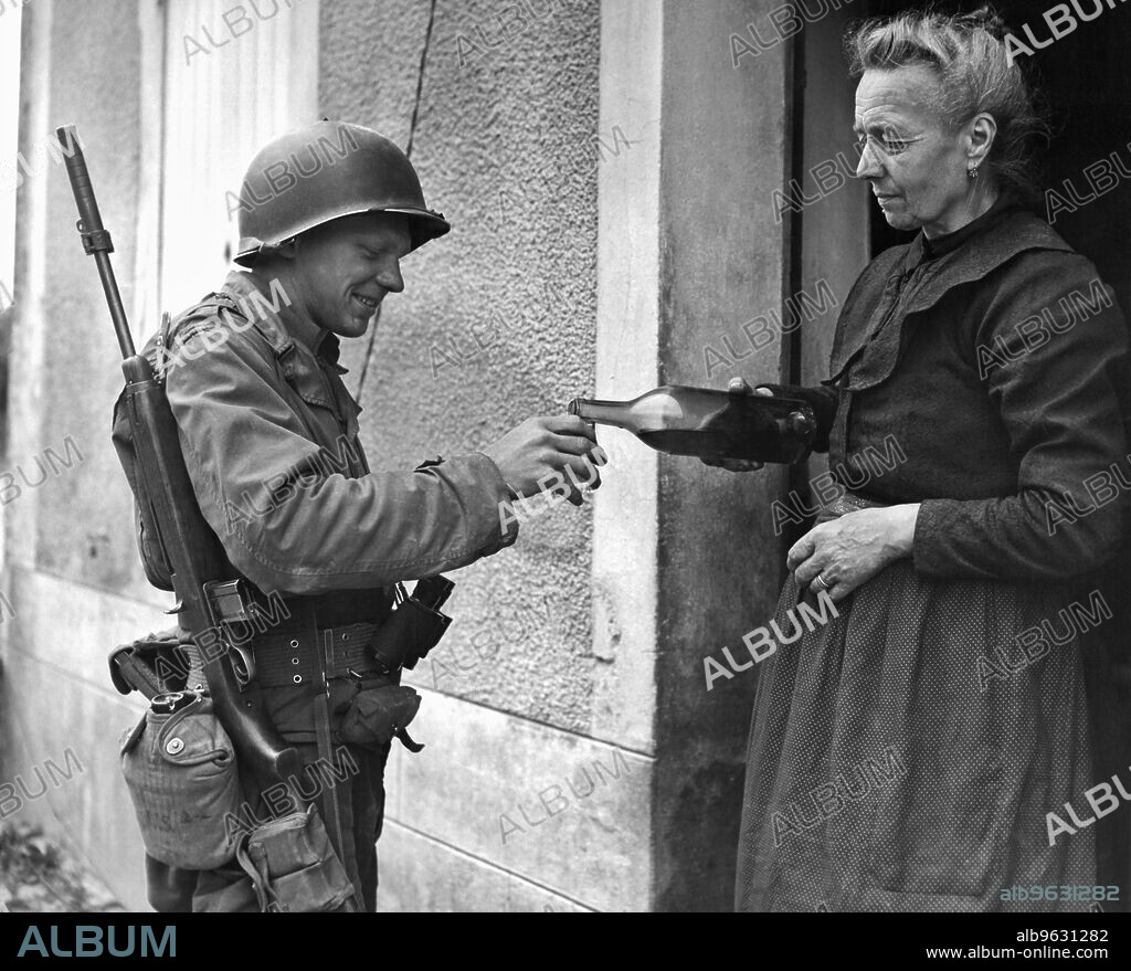 Marigny, France July 29, 1944 A 75 year old French woman offering wine to a US army soldier during World War II in Marigny, France.