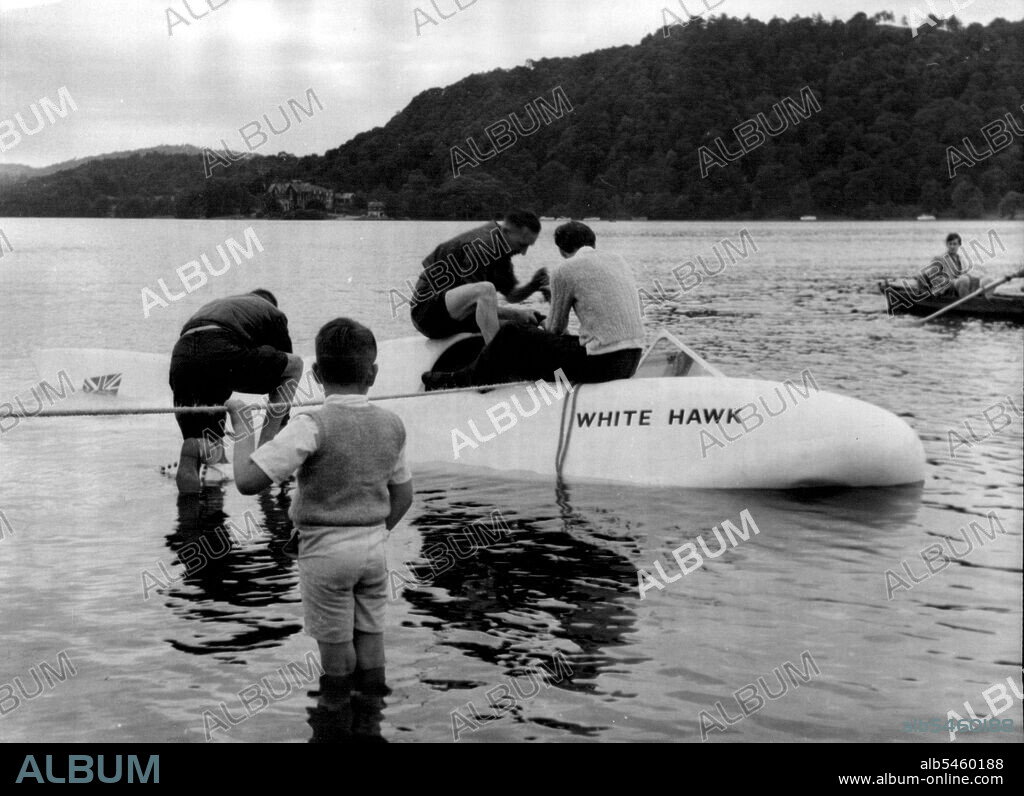 Jet-Boat Dives In Lake During Trial - The White Hawk being hauled to the shore after the mishap. Mr. Frank Hanning-Lee is seated on right.The £14,000 jet-propelled speed boat White Hawk, in which Mr. Frank Hanning-Lee, on naval officer, of Chelsea, London, and his wife Stella hope to rapture the the world's water speed record for Britain, dived briefly under the surface of the lake in a mishap during a trial run on Windermera, Mr. Hanning-Lee was piloting the boat when it was struck by side-wash from a pleasure boat. Water entered the air intake and the White Hawk dived nose first, filling with water. The cockpit went under water but the craft soon reappeared. Pleasure boats dashed to the assistance of White Hawk, which was towed 500 yards to the shore to be beached only superficial damage, and Mr. Hanning-Lee expects that the hull will have dried out in a couple of days.It is hoped that the record attempt may be made in two weeks' time over a measured mile on lake Windermere.The pr.