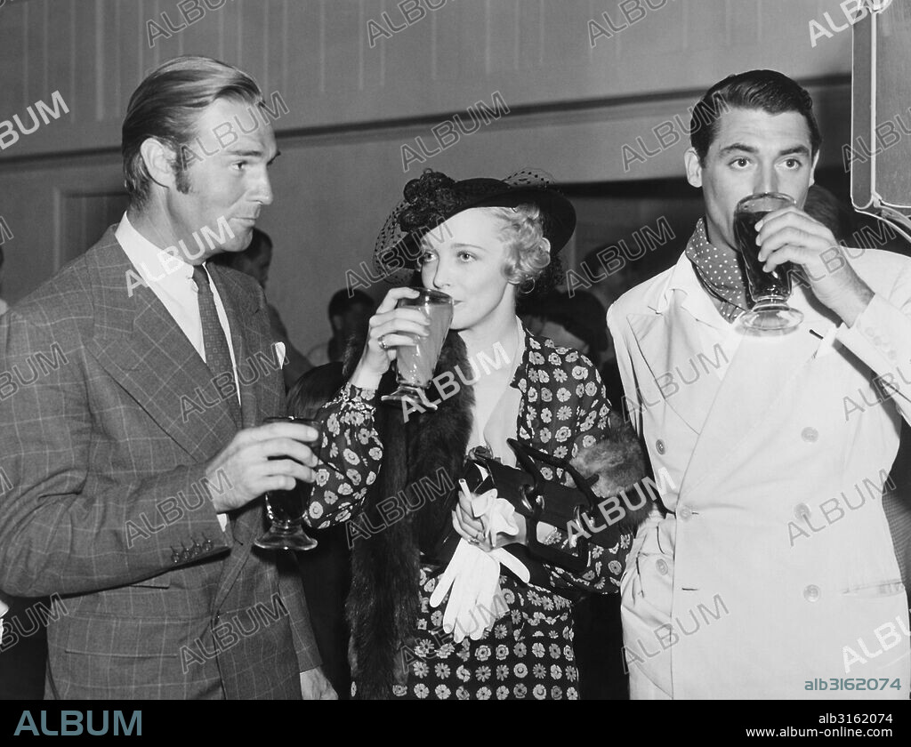 Hollywood, California: c. 1936. Movie stars Randolph Scott, Virginia Bruce and Cary Grant enjoying beverages at a Hollywood event.