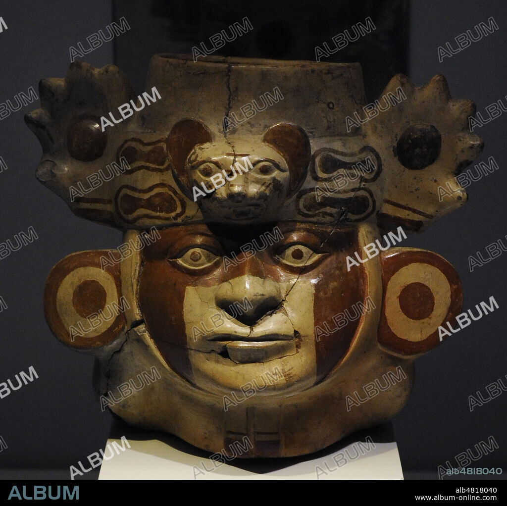 Vasija en forma de cabeza con pintura facial, orejeras y tocado en el que destacan los rasgos felinos. Cerámica. Cultura Mochica (100 a. C.-700 d. C.). Perú. Museo de América. Madrid. España.
