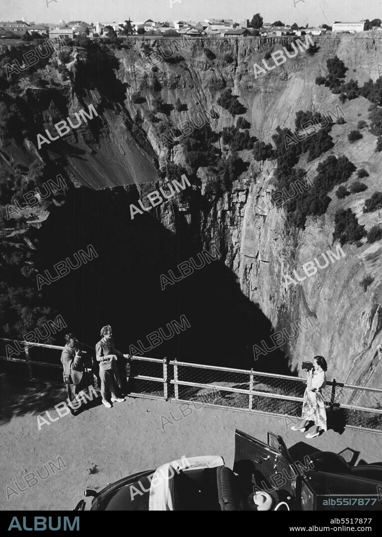 The Big Hole, Kimberley, South Africa - Kimberley, famous diamond centre of South Africa, has a unique tourist attraction in the form of a disused diamond mine, popularly known as "The Big Hole".Here the early diggers, working in the open with primitive equipment, excavated a gigantic crater 1,500 feet across and 1000 feet deep. Modern mining methods later extended the depth of the Big Hole to 4,000 feet, which during its life time yielded 15 million carats of diamonds valued at over £47,000,000. Kimberley lies 300 miles south west of Johannesburg, South African terminal of Qantas. October 10, 1952. (Photo by South African Tourist Corporation).