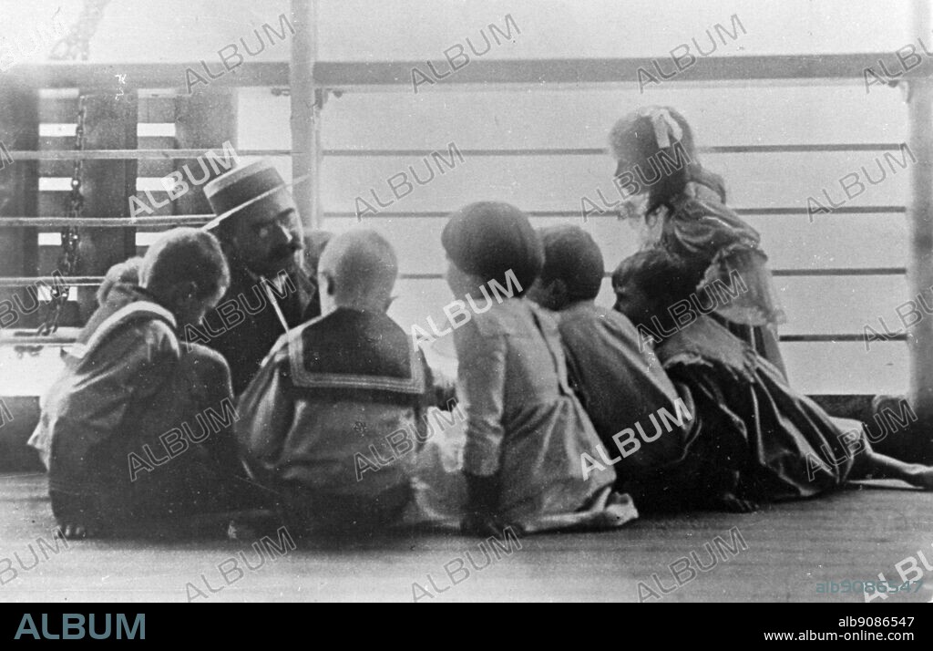 Rudyard Kipling on the way to Cape Town on a Union Castle Liner. He is said to be telling a Just So story to Elsie and John and some other children.