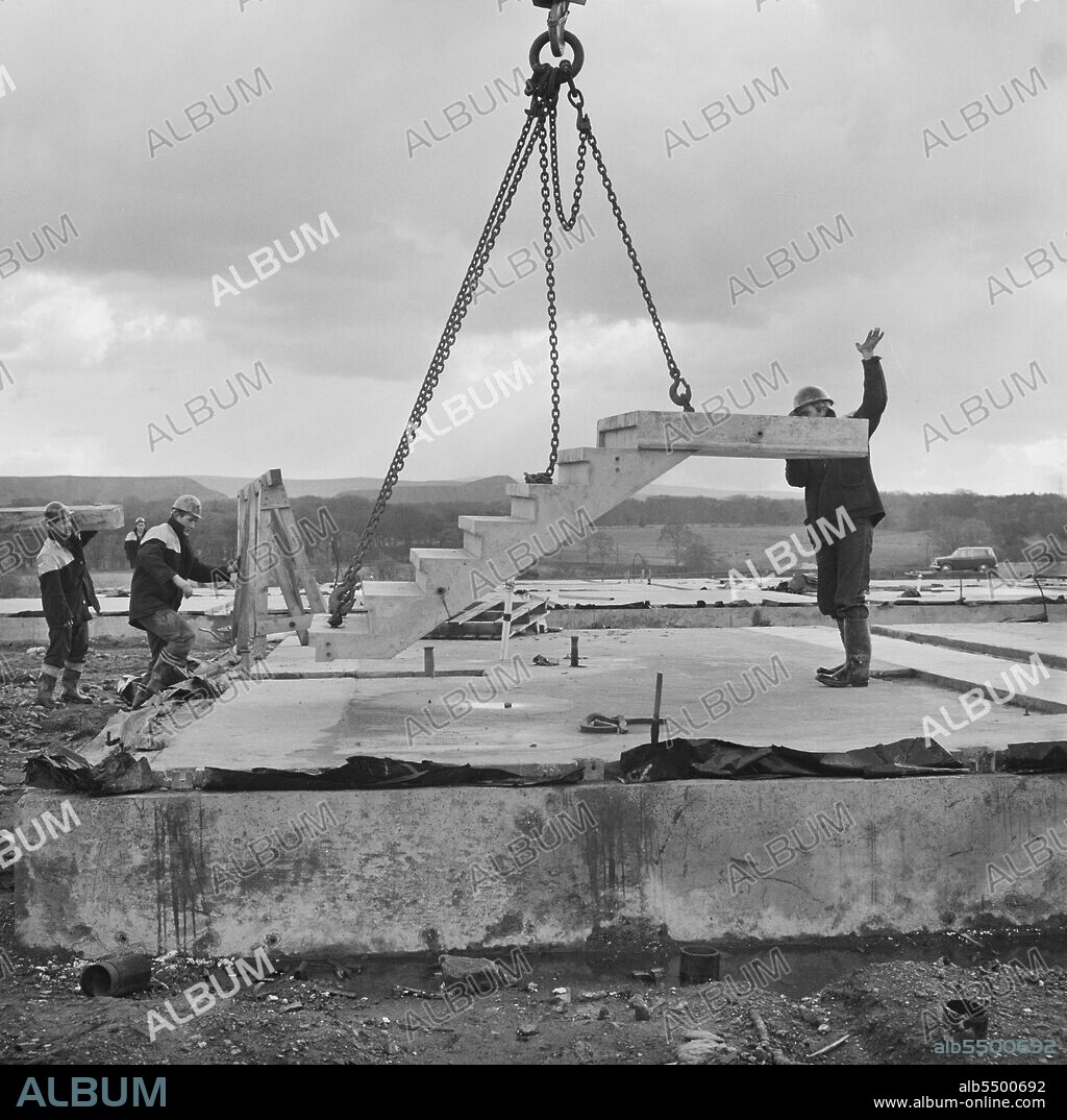 JOHN LAING PLC. Craigshill, Livingston, West Lothian, Scotland, 01/10/1965. A team of Laing workers lowering a prefabricated concrete staircase into position at a Jespersen construction compound, probably at the Craigshill development in Livingston. In 1963, John Laing and Son Ltd bought the rights to the Danish industrialised building system known as Jespersen (sometimes referred to as Jesperson). The company built factories in Scotland, Hampshire and Lancashire producing Jespersen prefabricated parts and precast concrete panels, allowing the building of housing to be rationalised, saving time and money. The location of this construction compound is uncertain, but it may have been at Craigshill in Livingston where there was a Jesperson Factory and a housing scheme built using the 12M Jespersen System.