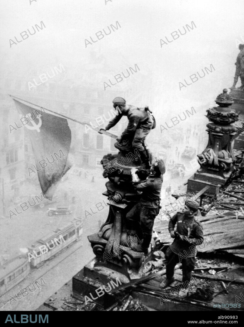 Following the fall of Berlin, russian soldiers raise the soviet flag of victory on top of the ruined Reichstag building. 2 May 1945.