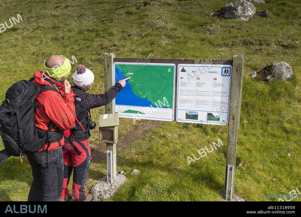 Hikers looking at maps, Gasadalur, Vagar Island, Faroe Islands, Denmark, Europe.