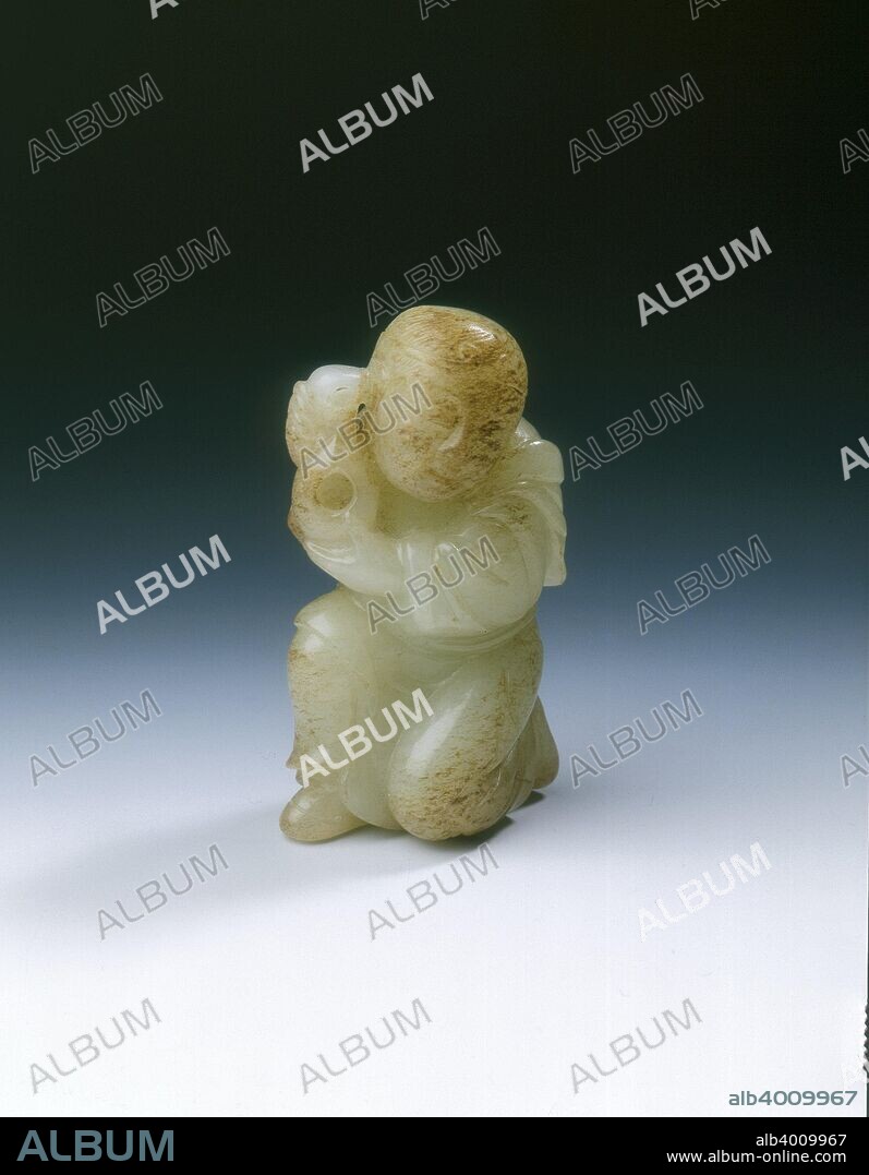 Yellowish jade kneeling tribute bearer, Tang or Liao dynasty, China, 8th-11th century. A jade figure of a tribute bearer kneeling on one knee the other leg bent. His hands are to one side holding up what may be a gourd lamp. The jade is of yellowish colour, the head and knee with brown suffusions. The long hair going down the back is in three short, but beautifully carved tresses, tied up by a circlet. The clothes are well done with a scarf round the shoulders.