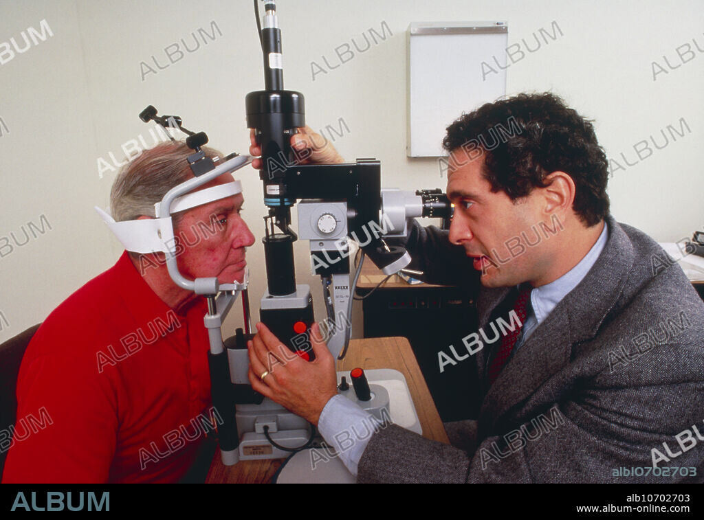 Eye surgery using an argon/krypton laser in a U.S. hospital: the patient's head is held in a brace whilst the doctor sets up the machine prior to commencing treatment. Northern Westchester Medical Centre, Mount Kisco, New York.