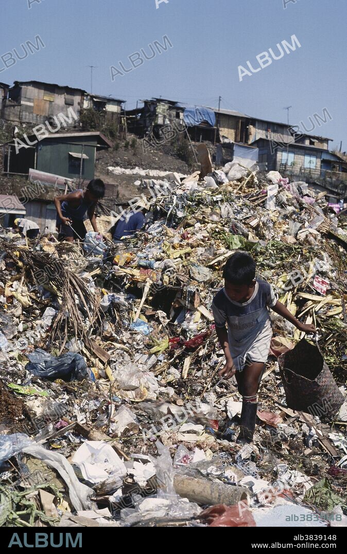 Young boys scavenge through trash on "smokey mountain". This huge dump in Manila consists of over two million tons of waste. Nearly 30,000 people live near the site, and make their living from picking through the garbage piles.