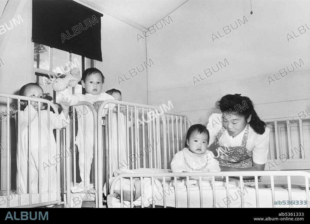Nurse tending to Orphan Infants in Nursery, Manzanar Relocation Center, California, USA, Ansel Adams, Manzanar War Relocation Center Collection, 1943.