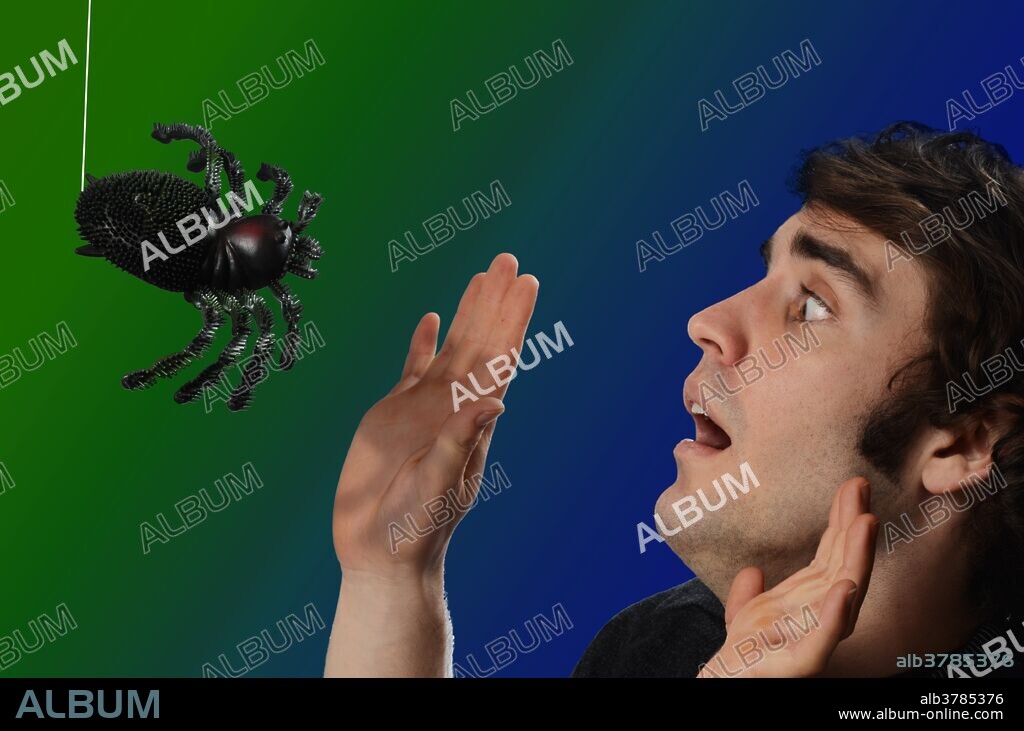 Man frightened by a spider. Fear of spiders, which are large, fast and hairy, is quite common. In extreme cases, such fear, known as arachnophobia, can be debilitating and may require psychological treatment.