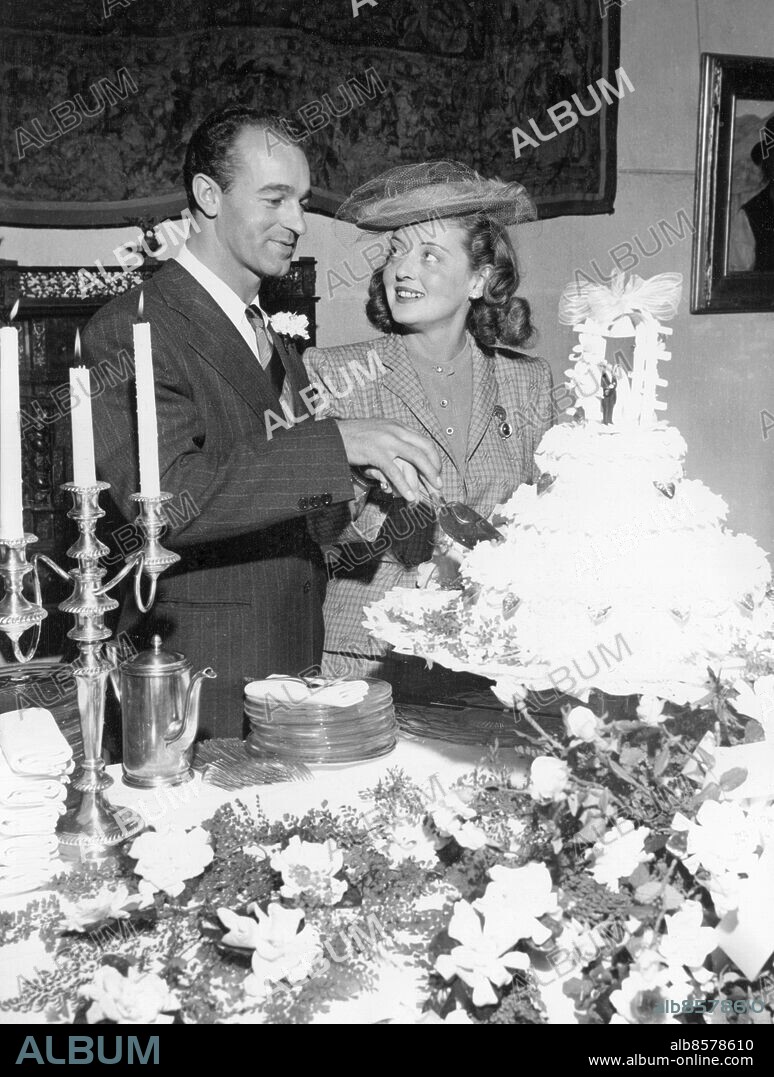 Orig. bildtext... DAVIS-SHERRY WEDDING FILMSTAR WEDS ARTIST AT RIVERSIDE! Riverside, Calif... Screen star Bette Davis and William Grant Sherry photographed immedatley after their marrige this afternoon as they cut their wedding cake. Ceremony was performed at the Mission Inn at Riverside Calif., after the episcopal diocese had refused to allow them to be married at miss Davis' own church because she had been previously divorced. Her uncle, an episcopal clergyman, assisted in ceremony which was performed by a congregational minister. Orig. bildtext... BRÖLLOPSKLOCKOR FÖR BETTE DAVIS. Filmstjärnan Bette Davis skär upp bröllopstårtan med sin make, William Grant Sherry. Vigseln ägde rum i Riverside. (...) Anm. För fullständig text se original B Davis, 1908-1989, amerikansk skådespelerska Bröllopstårtor Ljusstakar Blommdekorationer Tända ljus Bakverk Tårtor CD481 persons: WILLIAM GRANT SHERRY;BETTE DAVIS sites: KALIFORNIEN;USA.