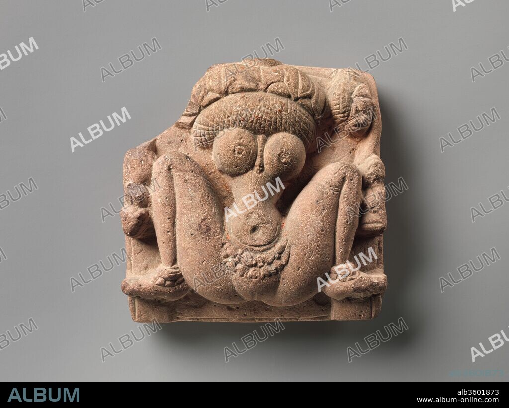 Lotus-Headed Fertility Goddess Lajja Gauri. Culture: India (Madhya Pradesh). Dimensions: H. 4 1/16 in. (10.3 cm); W.  4 1/16 in. (10.3 cm). Date: ca. 6th century.
Lajja Gauri is shown in a birthing posture but does not display the swollen belly of one about to give birth, which suggests that the image is of sexual fecundity. The lotus flower in place of her head makes this association with fertility explicit. This expression of the concept of the female body as the embodiment of life-affirming forces is perhaps the most extreme in Indian iconography. At her left is a diminutive kneeling figure, undoubtedly the donor. This miniature sculpture was reportedly found in the Seoni district of Madhya Pradesh, central India. Such imagery is rare and confined to the first millennium in central India and the Deccan.