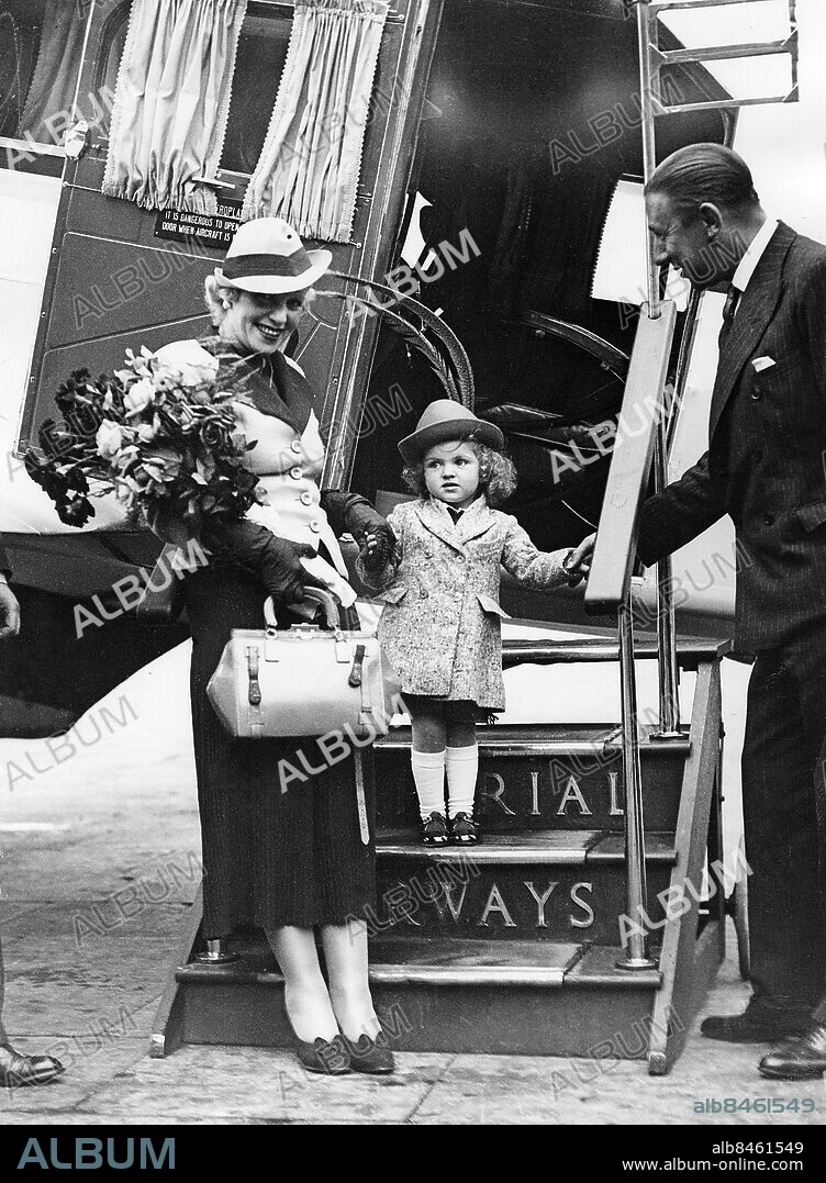 STORBRITANNIEN CROYDON 1936-06-10. Orig. bildtext... GITTA ALPAR FLIES TO ENGLAND FOR FILM. Gitta Alpar, famous Hungarian Prima Donna, arrived at Croydon this evening. She will star in a Tudor Film Production "Song of Love". Miss Alpar brought with her her little daughter Julie. O.P.S. Lord Ely, Chairman of the Tudor Film Production, assists Gitta Alpar's little daughter Julie, accompanied by Gitta Alpar, on their arrival at Croydon this evening. Foto: Keystone View Co. / AB Text & Bilder / SVT / Kod: 5600 Mapp: Alpar, Gitta G Alpar, 1903-1991, ungerskfödd sångerska, verksam i Tyskland, lämnade landet 1933. Gift med Gustaf Fröhlich 1931-1935 och fick en dotter, Julika. Resenärer Buketter persons: JULIKA ALPAR;GITTA ALPAR sites: STORBRITANNIEN;CROYDON;UNGERN*.