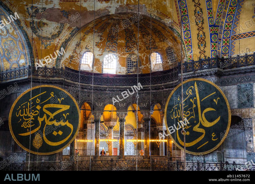 Caligraphy Roundels Naming Hasan, grandson of Mohammed (left) and Caliph Ali (right). Tourists Viewing from the Gallery, Interior, Hagia Sophia Grand Mosque, 537 AD, UNESCO World Heritage Site, Sultanahmet, Istanbul, Turkey.
