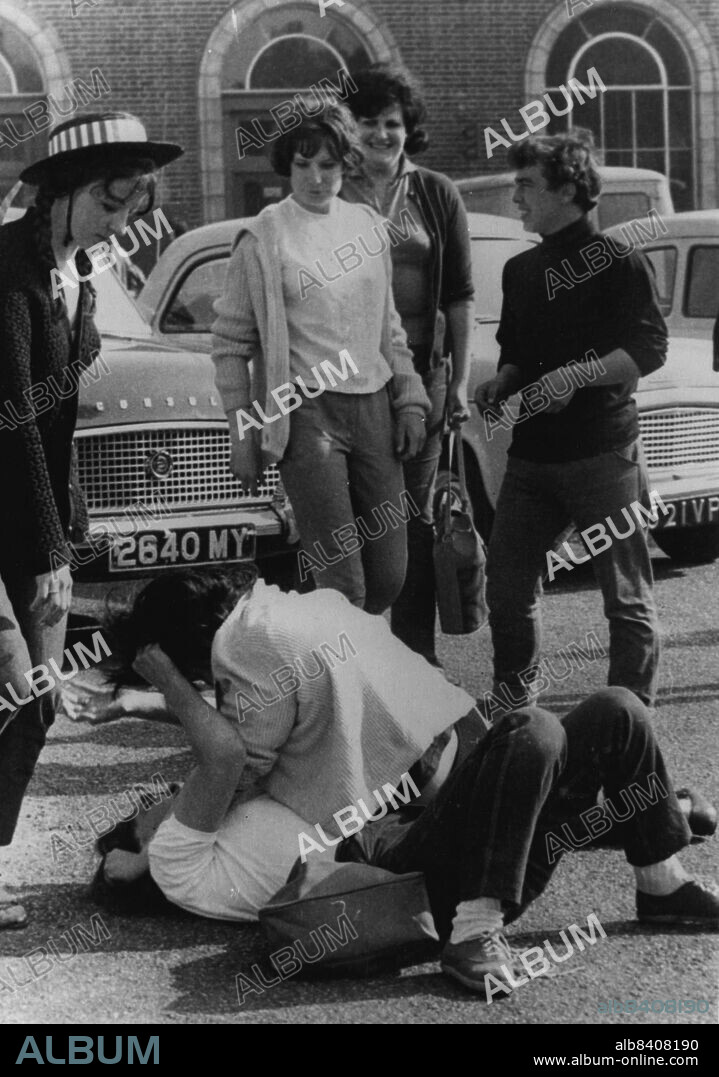 "Wild Ones" At It Again:As other grinning teenagers watch, two girls fight on the ground during yesterday's violence between rival gangs of "Mods" and "Rockers" in the seaside town of Margate, Kent. Two policemen were injured and 40 arrests made when gangs of weirdly clad, long-haired youths and girls, about 100 of whom had spent the night on the beach, fought with police on the seafront. Police leave was cancelled and reinforcement brought in from many parts of Kent. May 18, 1964. (Photo by United Press International).