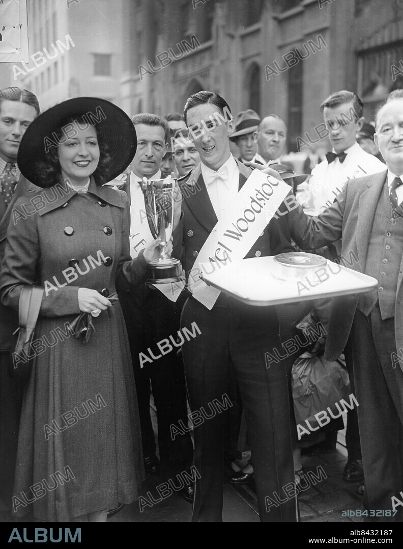 USA NEW YORK CITY omkring 1930.. Joe Callin, kypare från Woodstock Hotel, tar emot priset av Fay Marbe, amerikansk dansös, skådespelare och sångerska, efter att ha vunnit en löptävling för kypare i New York City. Foto: Underwood & Underwood / AB Text & Bilder / SVT / Kod: 5600. Engelsk originalbildtext.. Mapp: Sportkuriosa Kypartävling -1935 3563A. Servitörer Vinnare Segrare Priser Pokaler.
