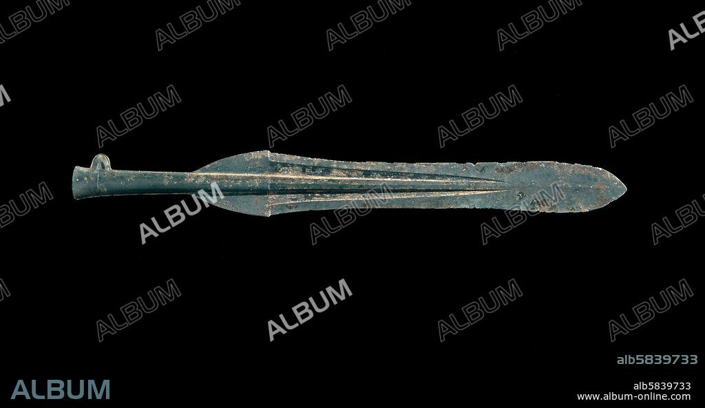Dôhoko (ritual spear blade), Yayoi period, Japan, c300 BC-300 AD. This bronze spear blade is said to have been excavated at Okamoto-chô, Kasuga City, in modern Fukuoka Prefecture. The blade has no attachment hole at the end, which suggests that it had no practical use but, like dôtaku and mirrors at the time, was made for burial in a ceremony possibly connected with agriculture. Its form is copied from a Chinese original. Iron and bronze were introduced into Japan at about the same time, so there was no recognizable 'Bronze Age' predating the use of iron. Iron was quickly recognized as the stronger of the two metals, more suitable for producing tools and weapons. Bronze was used for ritual objects such as mirrors, daggers and spears such as this one. JA, 1965.2-23.3.