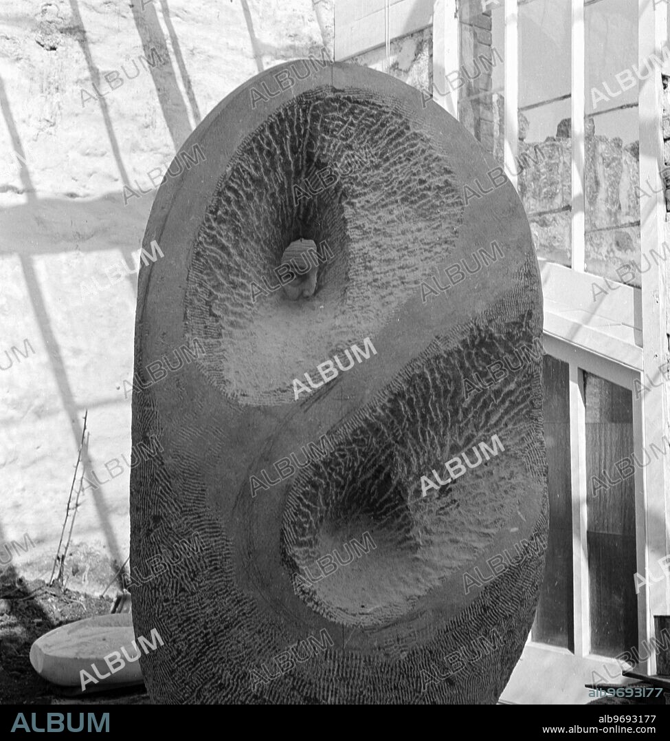 Barbara Hepworth photographed by Peter Keen of Pictorial Press in 1950. Barbara Hepworth standing behind one of her sculptures and peeking through - this sculpture in progress is her 'Memorial sculpture to Duncan Macdonald', 1950. Artist copyright: Barbara Hepworth © Bowness. 1950 Barbara Hepworth - her studio and garden. She purchased the site in 1949 and lived and worked there for 26 years until her death in a fire on the premises in 1975. Barnoon Hill, St Ives.