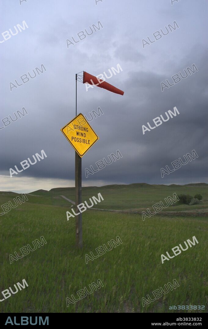 'Strong Wind Possible' sign beneath a stormy sky in Wyoming showing a windsock in strong winds.