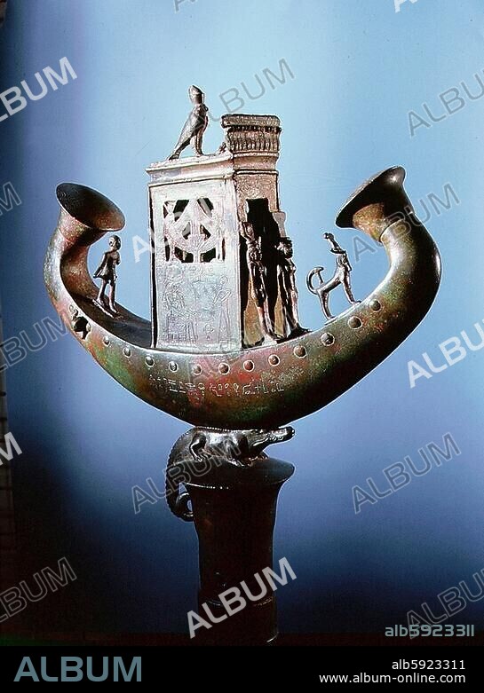 Insignia in the form of a solar barque dedicated to Djedher, used in Nile processions and funerary rites. The boat hold a temple containing the enthroned sun god Amun-Re, surmounted by Horus and a uraeus, with images of Isis and Nephthys. It rests on a cro (..).