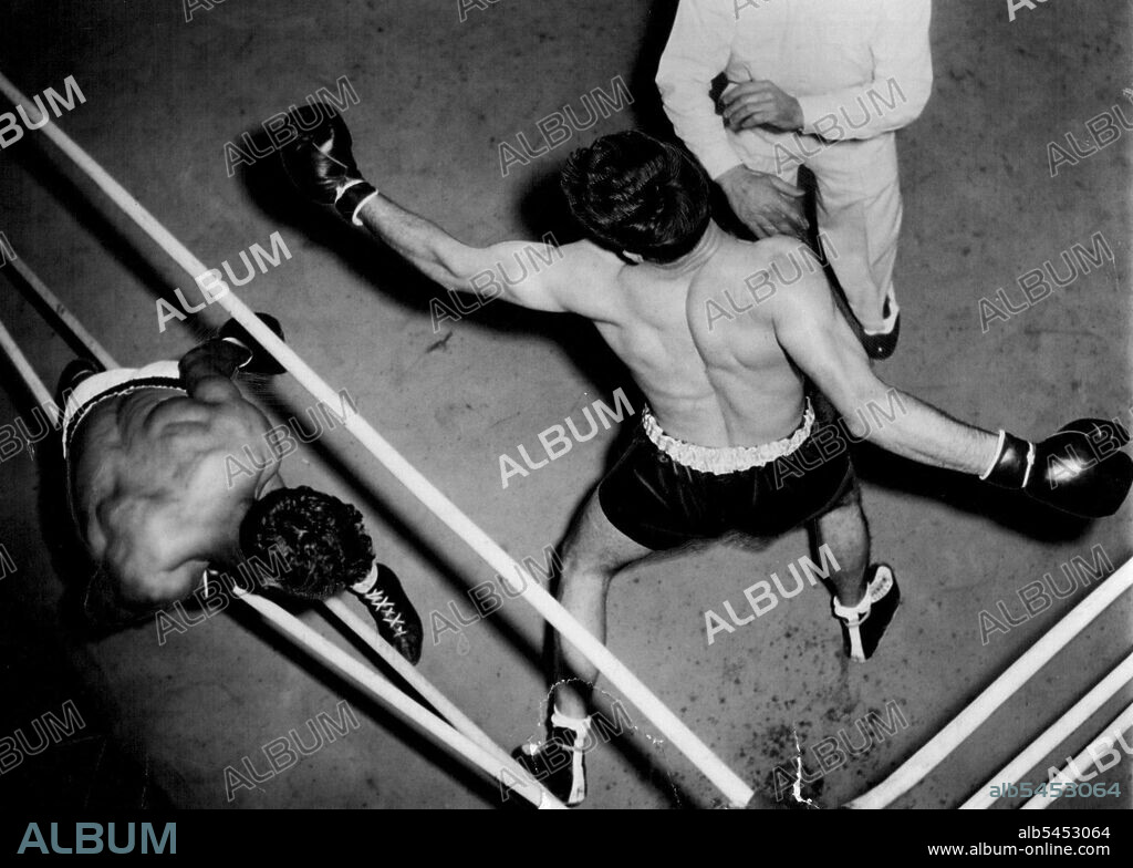 Don Johnson about to let go with a wild right swing as Alf Sands is halfway through the ring strands during last night's Stadium fight. The punch landed on Sands over the top strand. September 15, 1953.