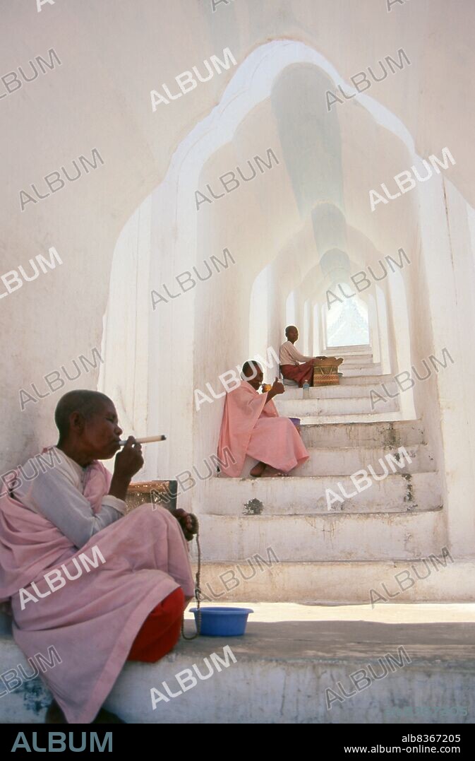Burma / Myanmar: Buddhist nuns on a staircase at the Hsinbyume Pagoda, close to the Mingun Pahtodawgyi (Mingun Temple), Sagaing District, near Mandalay. The Hsinbyume Pagoda was built in 1816 by King Bagyidaw (1784 - 1846), the seventh king of the Konbaung Dynasty. He built it for his first wife, Princess Hsinbyume who died in childbirth in 1812. The pagoda is also known as the Myatheindan Pagoda. The pagoda's design is based on the mythical Sulamani Pagoda found on Mount Meru, with the seven lower concentric terraces representing the mountain ranges leading to Mount Meru.