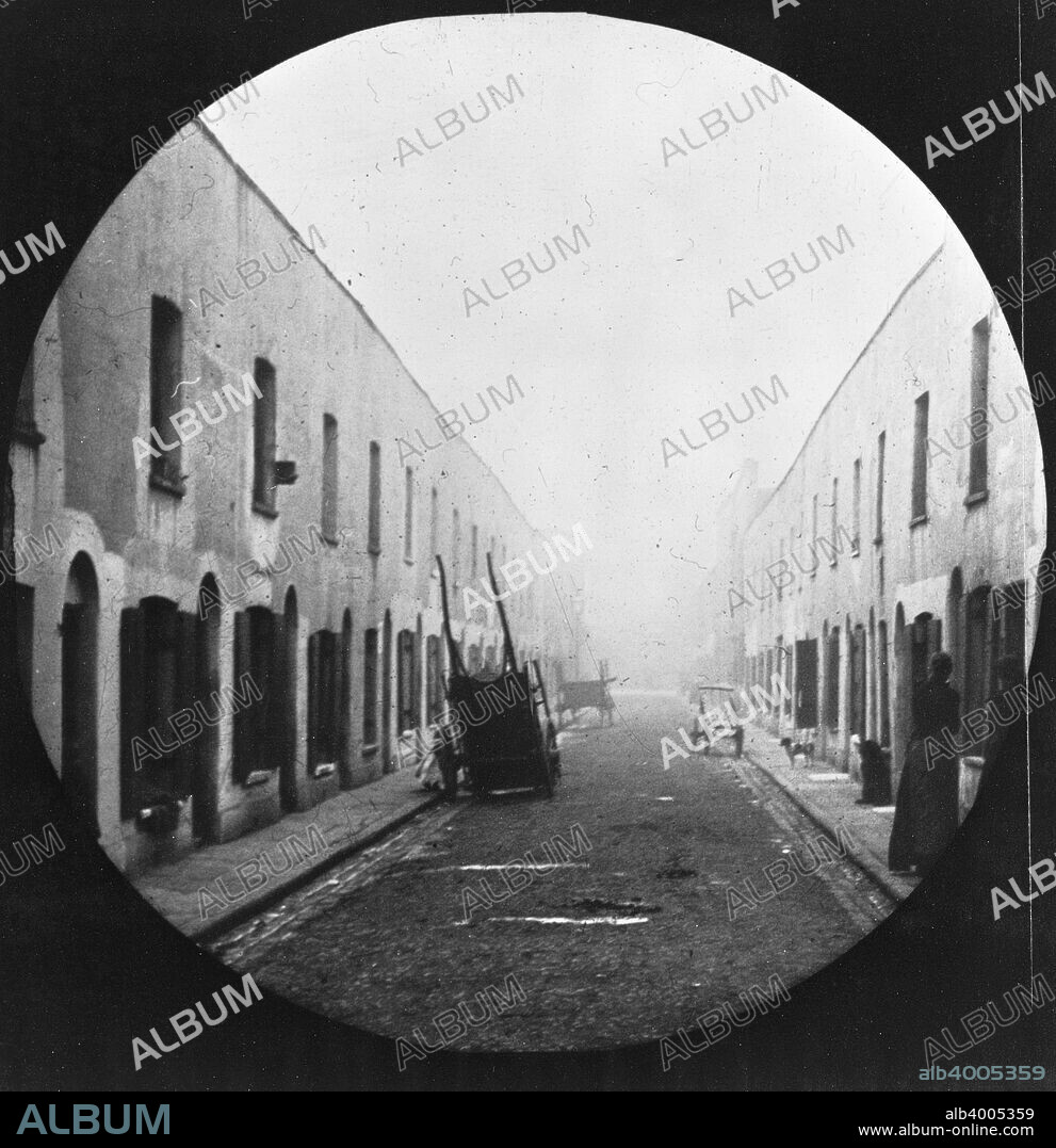Neath Place, London, c1900. A run down street with three barrows left deserted in the road. Galt came to London in 1890 to work as a missionary for the London City Mission. In the early 1900s he took a series of photographs, mainly of the East End, which he had made into lantern slides to illustrate lectures publicising the work of the Mission. Galt sought to show that though there was great poverty in the East End, the people were not sub-human, as was popularly imagined by the middle-classes, but ordinary folk trying to do their best under difficult circumstances.