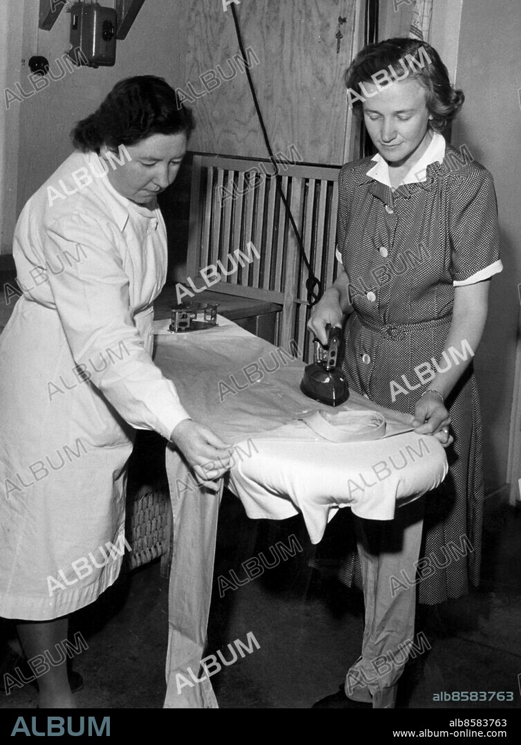 SEKLET SAMHÄLLE-40 - Stockholms stads tvätt-och strykskola på Swedenborgsgatan fick många anmälningar till sin första kurs i strykning för husmödrar i juni 1947. Främst är det herrskjortor som husmödrarna ville lära sig stryka fint. Bilden visar hur fröken Daga Nordh visar fru Naima Windelhed hur strykningen av en herrskjorta går till. Foto: Dagens Nyheter Kod: 192/9909 . COPYRIGHT SCANPIX SWEDEN.