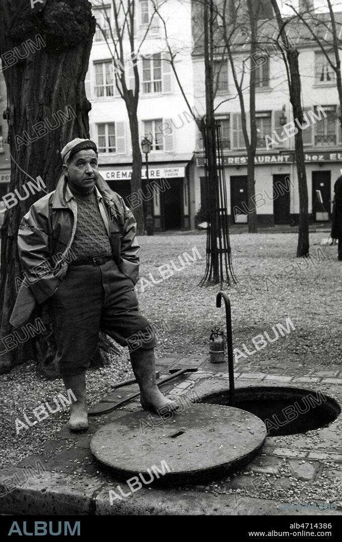 Egouttier devant une bouche d'egout, voierie parisienne, employe municipal. Scene de rue, Vie quotidienne, dans la ville, Paris, 1958, annees 50. Photographie JEAN POTTIER. Credit photo JEAN POTTIER/KHARBINE TAPABOR.