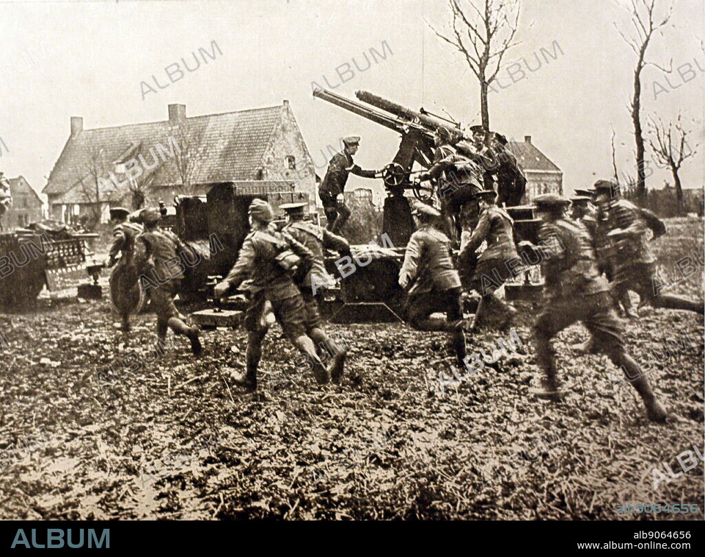A photograph from the First World War, showing soldiers running into an area while two gunners man an anti aircraft gun just next to them. Circa 1914-1918.
