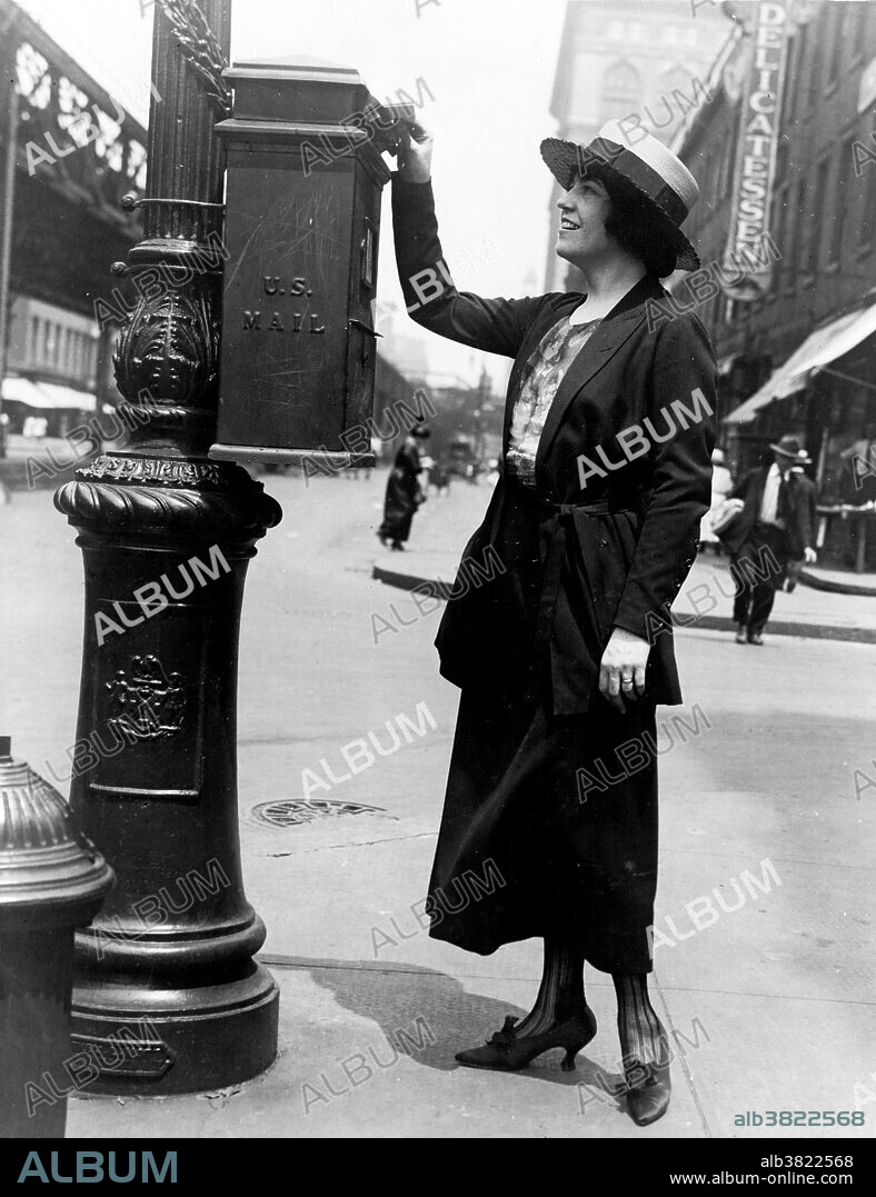 Entitled: "Merle Alcock (Metropolitan Opera contralto) mailing a letter in New York City" shows a woman putting a letter in a U.S. Mailbox attached to a post on a street corner. A post box, also known as a collection box, mailbox, letter box or drop box is a physical box into which members of the public can deposit outgoing mail intended for collection by the agents of a country's postal service. The United States Post Office Department began installing public mail collection boxes in the 1850s outside post offices and on street corners in large Eastern cities. Collection boxes were initially designed to be hung or supported, and were mounted on support pillars, lamp-posts, telegraph poles, or even the sides of buildings. By the 1880s, these pillar boxes were made of heavy cast iron to deter theft or vandalism. As mail volume grew, the Post Office Department gradually replaced pillar mailboxes with larger free-standing models, though many of the pillar boxes continued in service as late as the 1960s. Bain News Service, 1920s.