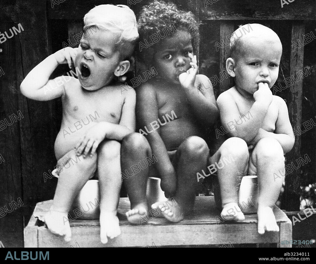 Orig. bildtext... SCULPTURE IN EBONY AND IVORY Heidelberg, Germany.... One of the many headaches of German welfare authorities is what to do about the hundreds of babies, born of american fathers and german mothers, that have been abandoned by their mothers for economic and social reasons. Such children represent a high precentage of the population of german orphanages and nursing homes. This trio was photographed at a catholic home in Heidelberg. The babies happily know nothing of racial discrimination. Here, Anna (center) and two little tow-heads are enthusiastically nonchalant, not to say bored, as the photographer intrudes on their privacy. Anm. Naket Ansiktsuttryck Efterkrigstid Gäspningar Föräldralösa barn Jämförelser Trio sites: HEIDELBERG;TYSKLAND.