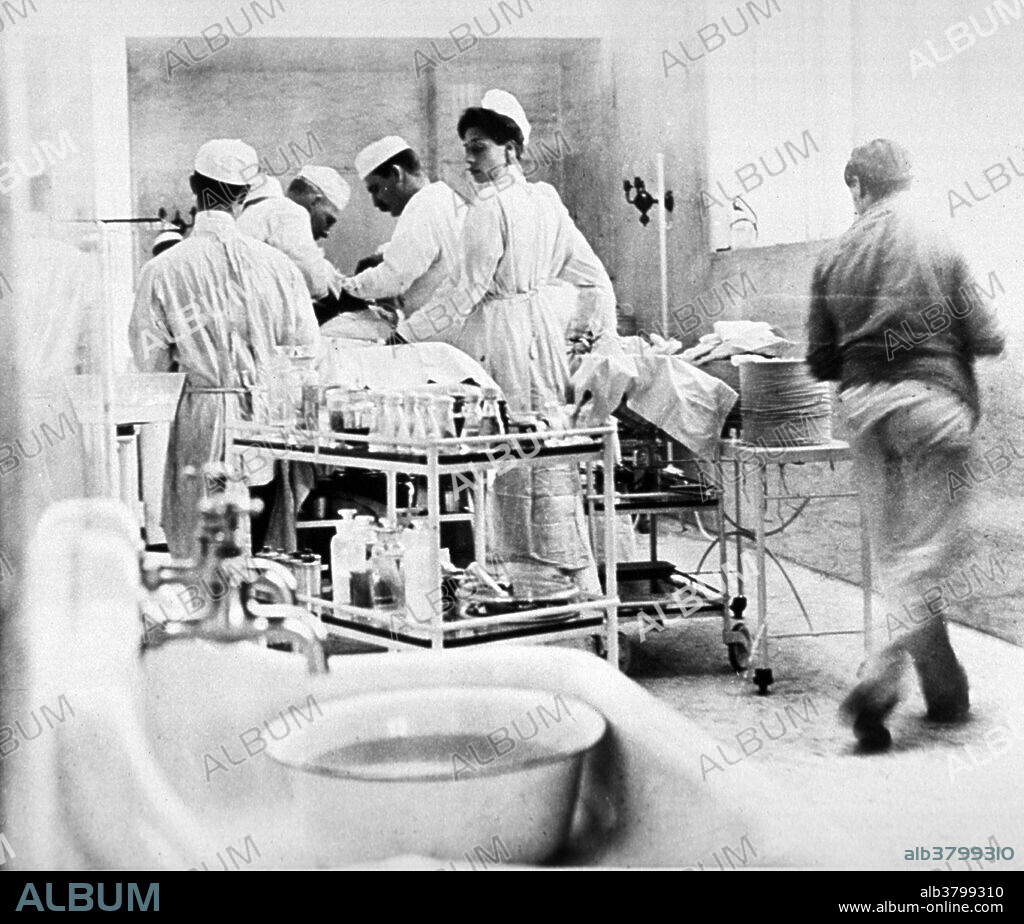 American surgeon William Stewart Halsted (1852-1922) and attending surgeon Finney operating on a patient. Halsted emphasized strict aseptic technique during surgical procedures, was an early champion of newly discovered anesthetics, and introduced several new operations, including the radical mastectomy for breast cancer. He also introduced the hospital chart which tracks the patient's temperature, pulse and respiration. Halsted was the first chief of the Department of Surgery at Johns Hopkins Hospital when it opened in May 1889. He was appointed surgeon-in-chief in 1890 and became Professor of Surgery in 1892 with the opening of Johns Hopkins University School of Medicine. He was credited with starting the first formal surgical residency training program in the United States. Photograph from the Johns Hopkins hospital album, Baltimore, 1903-1904.