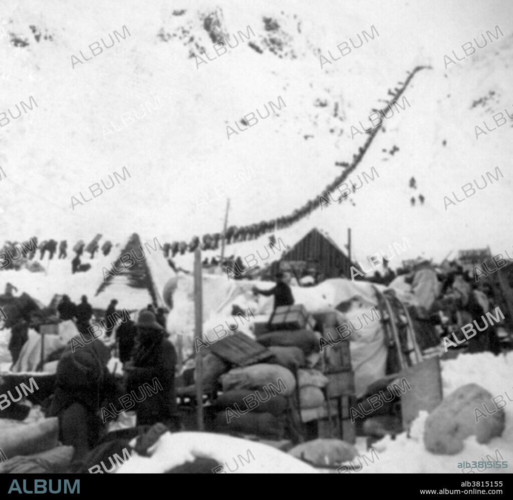 Bound for the Klondike Gold Fields, Chilcoot Pass, Alaska. The Klondike Gold Rush was a migration by an estimated 100,000 prospectors to the Klondike region of the Yukon between 1896-99. Gold was discovered by local miners on August 16, 1896 and, when news reached Seattle and San Francisco, it triggered a stampede of would-be prospectors. To reach the gold fields most took the route through the ports of Dyea and Skagway in Alaska. Here, the Klondikers could follow either the Chilkoot or the White Pass trails to the Yukon River and sail down to the Klondike. Each of them was required to bring a year's supply of food by the Canadian authorities in order to prevent starvation. In all, their equipment weighed close to a ton, which for most had to be carried in stages by themselves. Together with mountainous terrain and cold climate this meant that those who persisted did not arrive until summer 1898. Mining was challenging as the ore was distributed in an uneven manner and digging was made slow by permafrost. In the summer of 1899, gold was discovered around Nome in west Alaska, and many prospectors left the Klondike for the new goldfields, marking the end of the rush. Gold mining activity lasted until 1903. Cropped stereograph card, Keystone View Company, 1898.