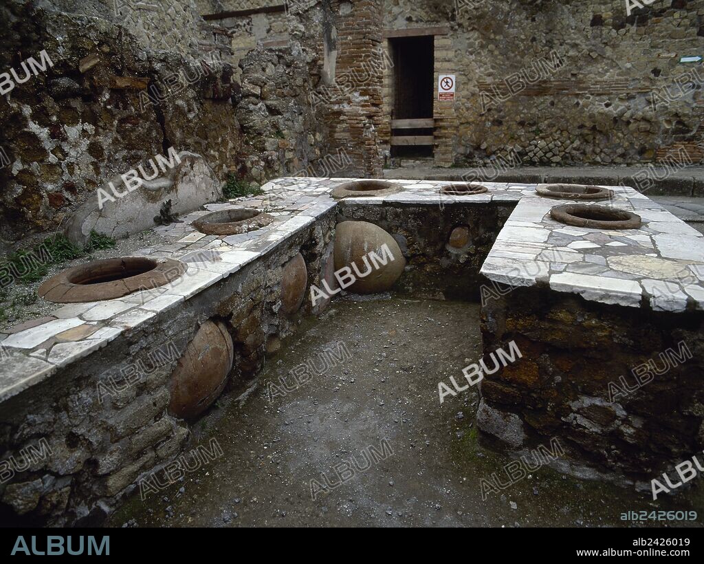 ARTE ROMANO. ITALIA. "TERMOPOLIO". Taberna especializada en la venta de bebidas calientes. Vista general de la barra de piedra con huecos donde se encuentran colocadas las ánforas que contenían las escancias de las bebidas. HERCULANO. La Campania. Italia.