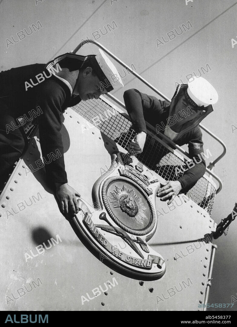 HMAS Anzac, prepares for Korean - This shot shows the new crest of the ship being put into place on the bridge work today. This is the proud crest "United We Stand" LtoR: ***** Seymour & A/BJ E. Cooper. July 25, 1951.