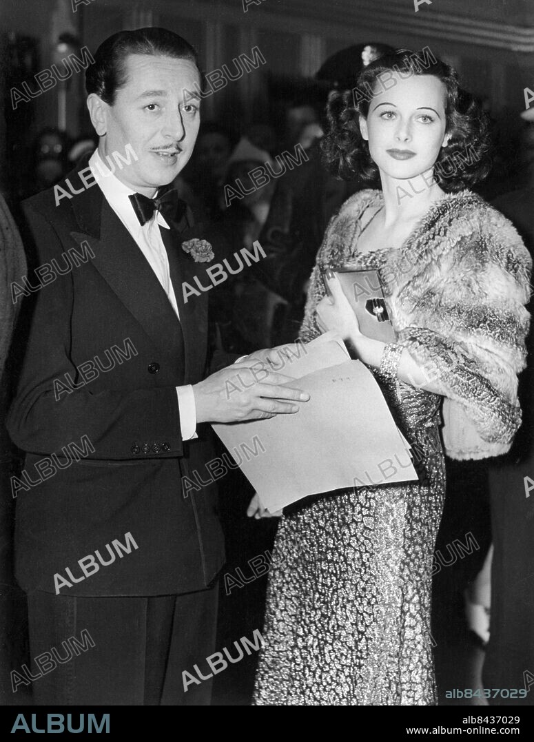 Orig. bildtext... FILM STARS SHINE AT ALGIERS PREMIERE Hollywood, Cal. Hedy Lamarr in Algeiers, new Walter Wanger film, was the attraction that brought the biggest names in Hollywood out for the colony's second big premiere in less than a week, July 13. Among those attending were Miss Lamarr and Norma Shearer, whose latest starring pictured was premiered the week before. Photo shows: Hedy Lamarr, making her American film debut, with Reginald Gardner, English comedian, at the premiere. She is wearing a chinchilla cape over a dress of silver and blue lame. Anm. H Lamarr, 1913-2000, amerikansk skådespelerska född i Österrike. R Gardiner, 1903-1980, engelsk skådespelare. CD443 persons: REGINALD GARDNER;HEDY LAMARR sites: HOLLYWOOD;USA.