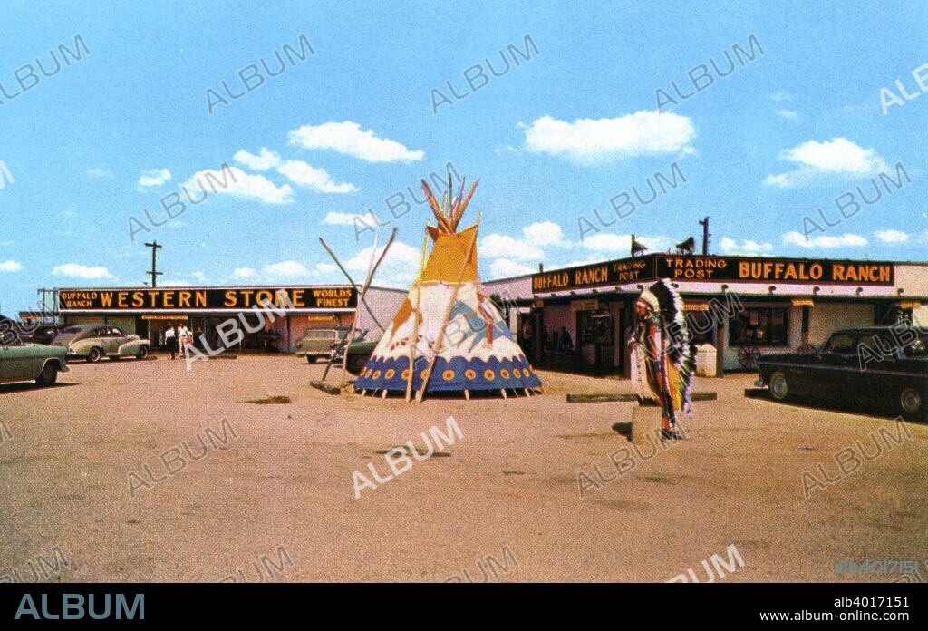 Buffalo Ranch Western Store and Trading Post, Afton, Oklahoma, USA, 1958. Vintage postcard. A Native American man and teepee are in the parking lot and cars are parked alongside the buildings.