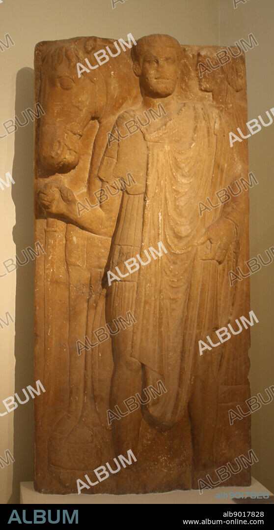 Grave stele. Peloponnesian marble, found in Mantineia, Arkadia. The dead man is depicted as an officer wearing military uniform, holding two spears. Behind him can be seen a female, probably his wife. AD 225-250.