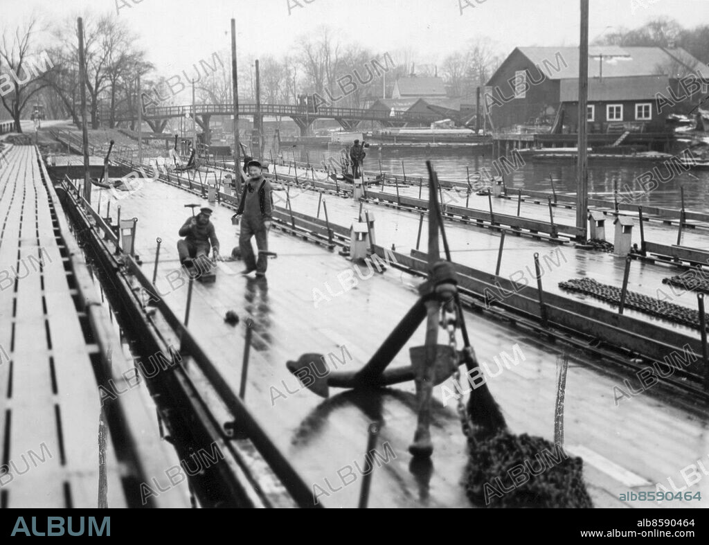 Stockholm 1933-01-01. Pontonbron som vintertiden förbinder Söder Mälarstrand och Munkbron har nu plockats fram, och man är som bäst i färd med att rusta upp den för vinterkampanjen.. Foto: DN / TT / Kod: 192. ** SvD OUT **.